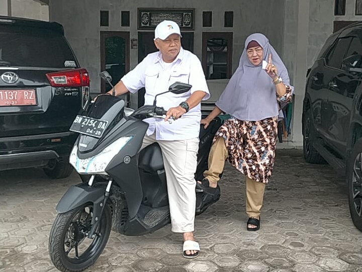 Caption Calon Bupati Bangka Barat, Sukirman membonceng istrinya, Rosmala menuju TPS 01 Desa Pusuk, Kecamatan Kelapa, Kabupaten Bangka Barat, Rabu (27/11/2024).